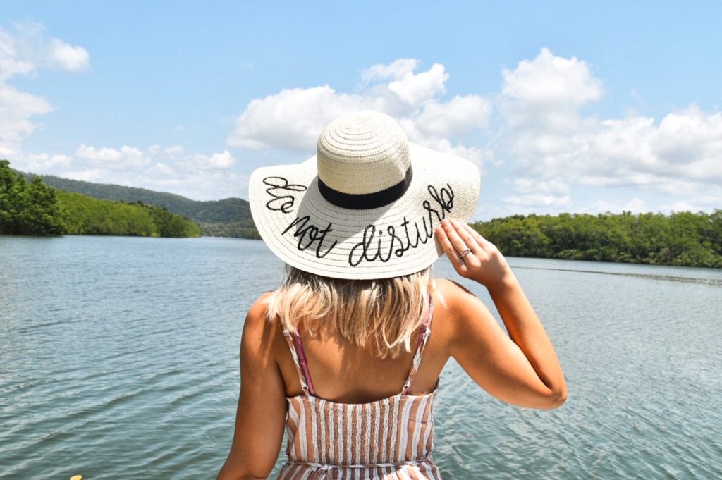 Blonde girl in pretty dress wearing a sunhat that says Do Not Disturb