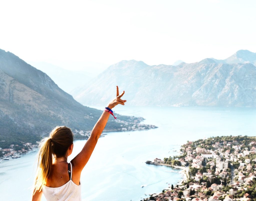 Sarah Latham looking out with hand raised over Kotor Old Town in Montenegro