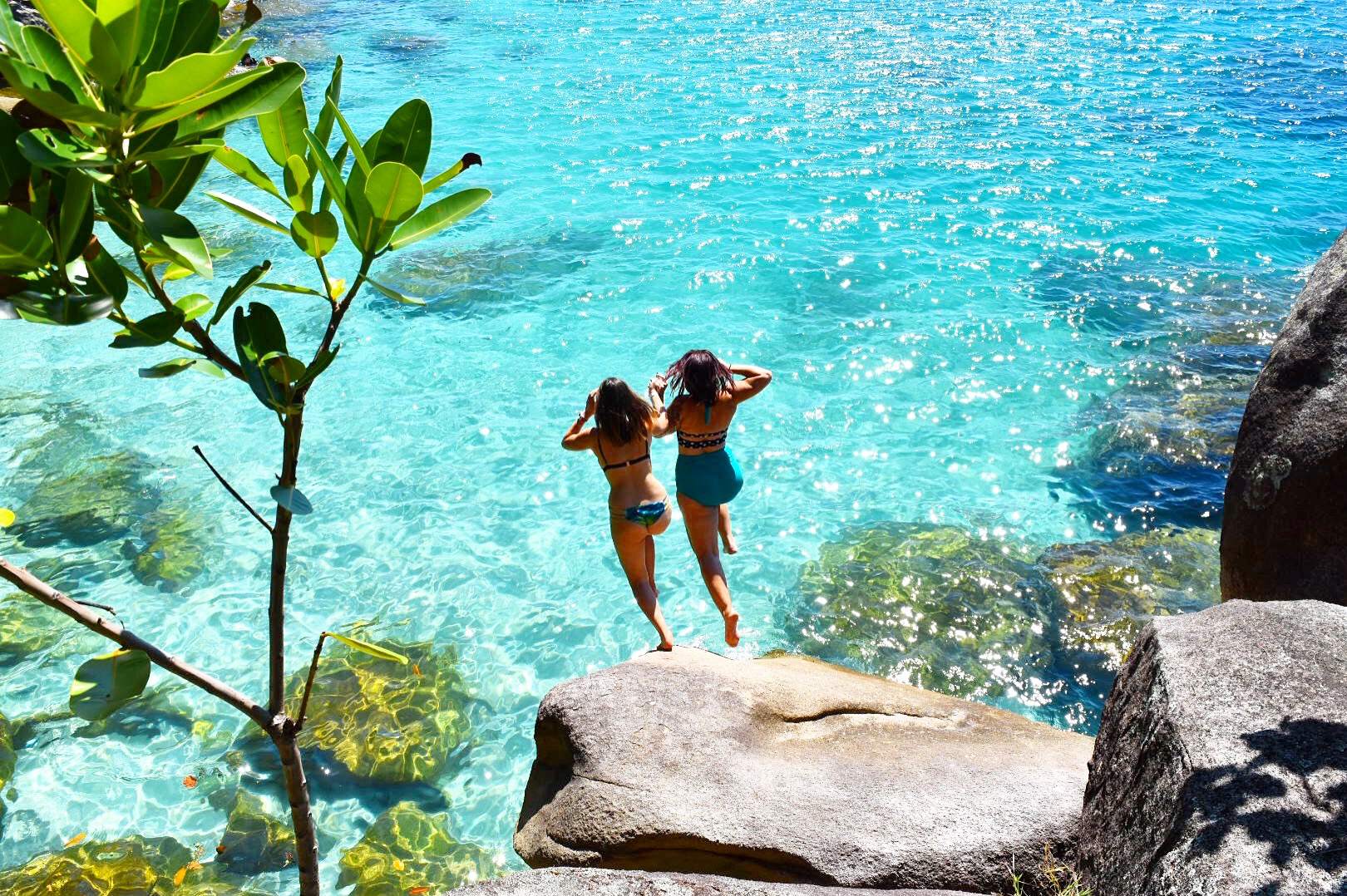 Two girls jumping into water at Nudey Beach Fitzroy Island