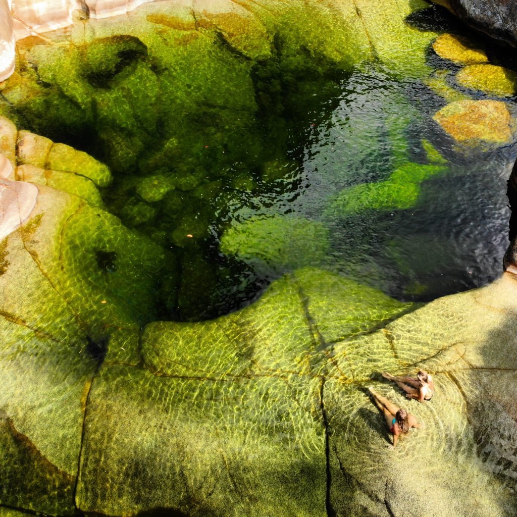 Two girls sitting next to very large green rock pool