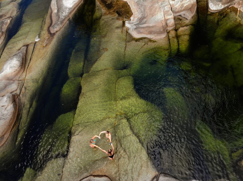 Three girls making love heart with their hands at a very large clear green rock pool in Behana Gorge in Cairns