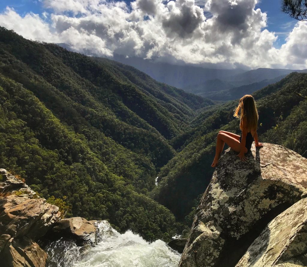 Girl sitting overlooking the top of Windin Falls waterfall