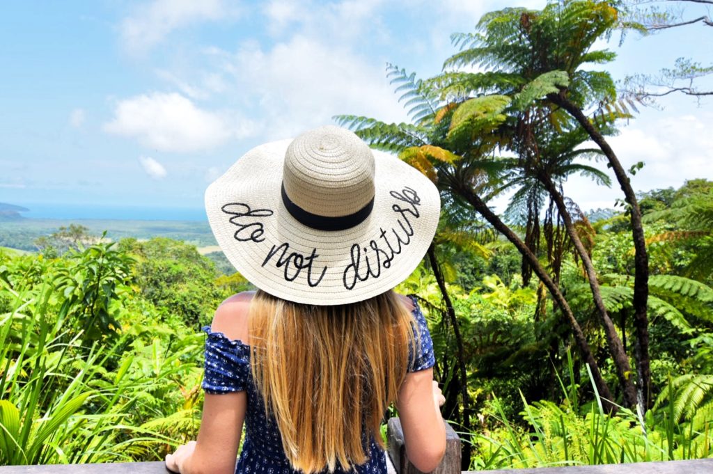 Girl standing with a sunhat that says "Do not Disturb"