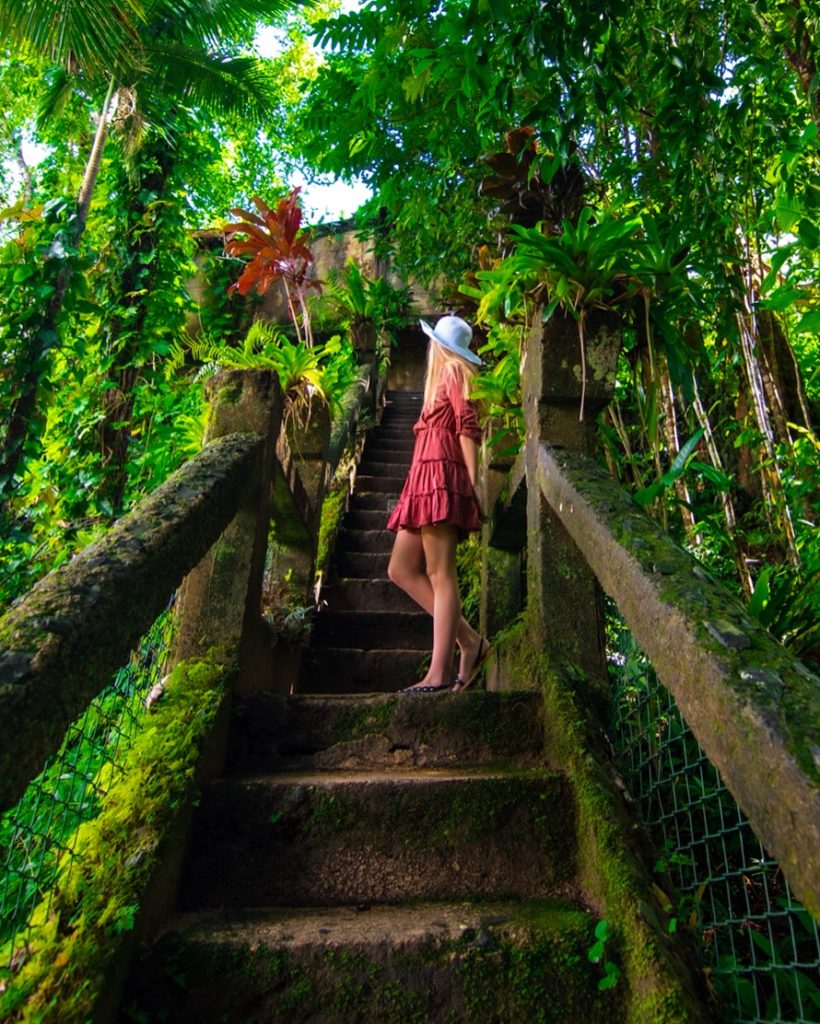 Girl standing on grand staircase in rainforest at Paronella Park